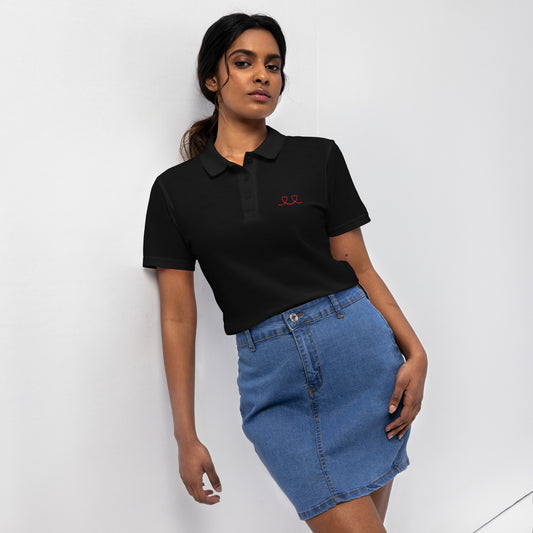 Woman wearing a black pique polo shirt with a red love smiley embroidery and a blue denim skirt on a white background