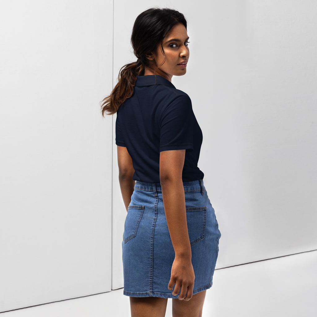 Woman wearing a navy polo shirt with a red love smiley embroidery and a blue denim skirt on a white background. Photography taken from back.