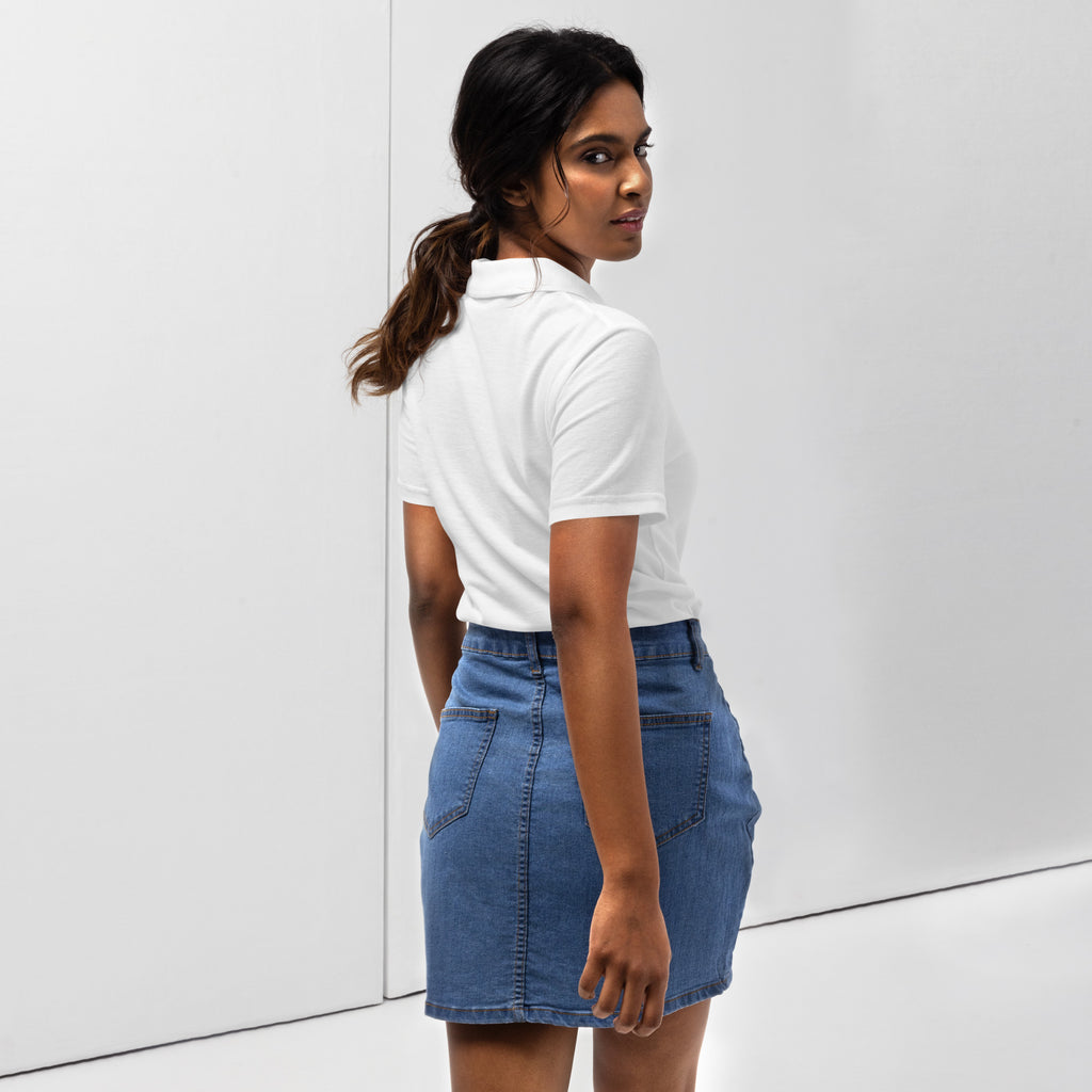 Woman wearing a white pique polo shirt with a red love smiley embroidery and a blue denim skirt on a white background. Photo taken from the backside.