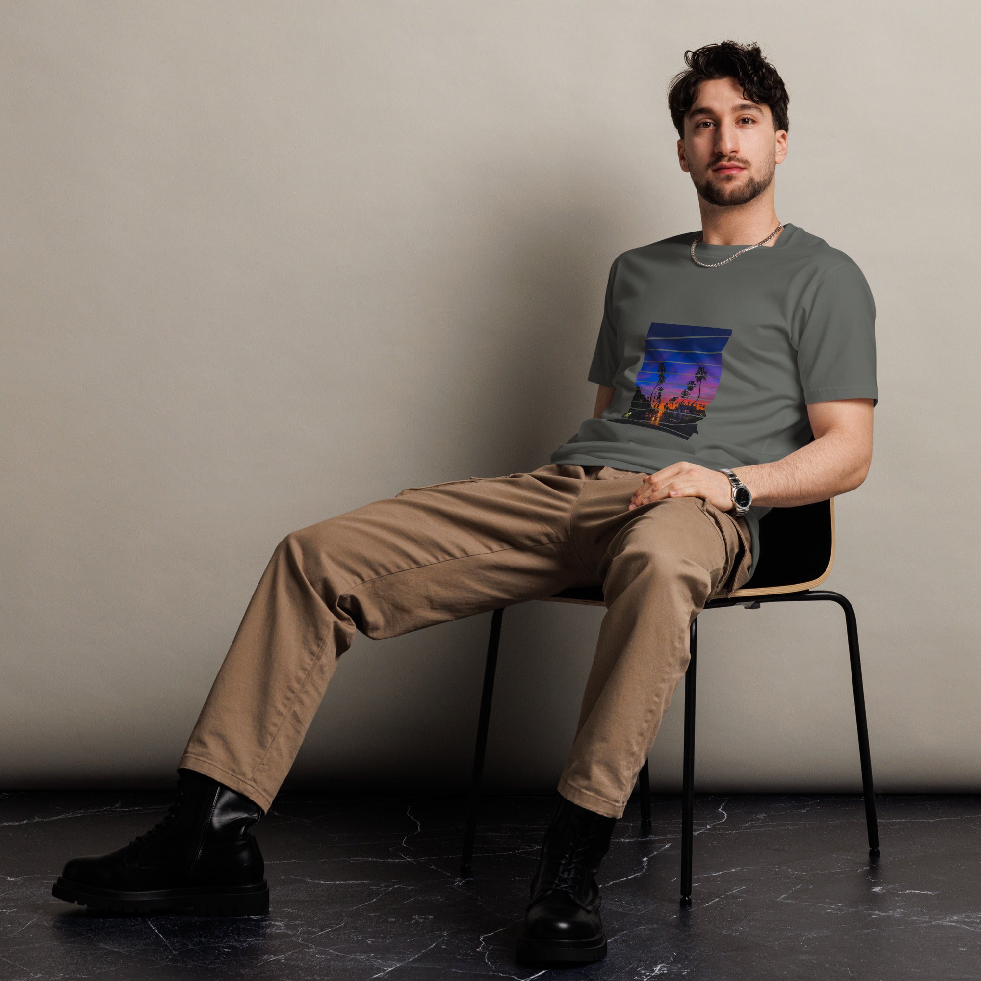 Man sitting on a chair wearing a graphic sunset t-shirt against a plain background