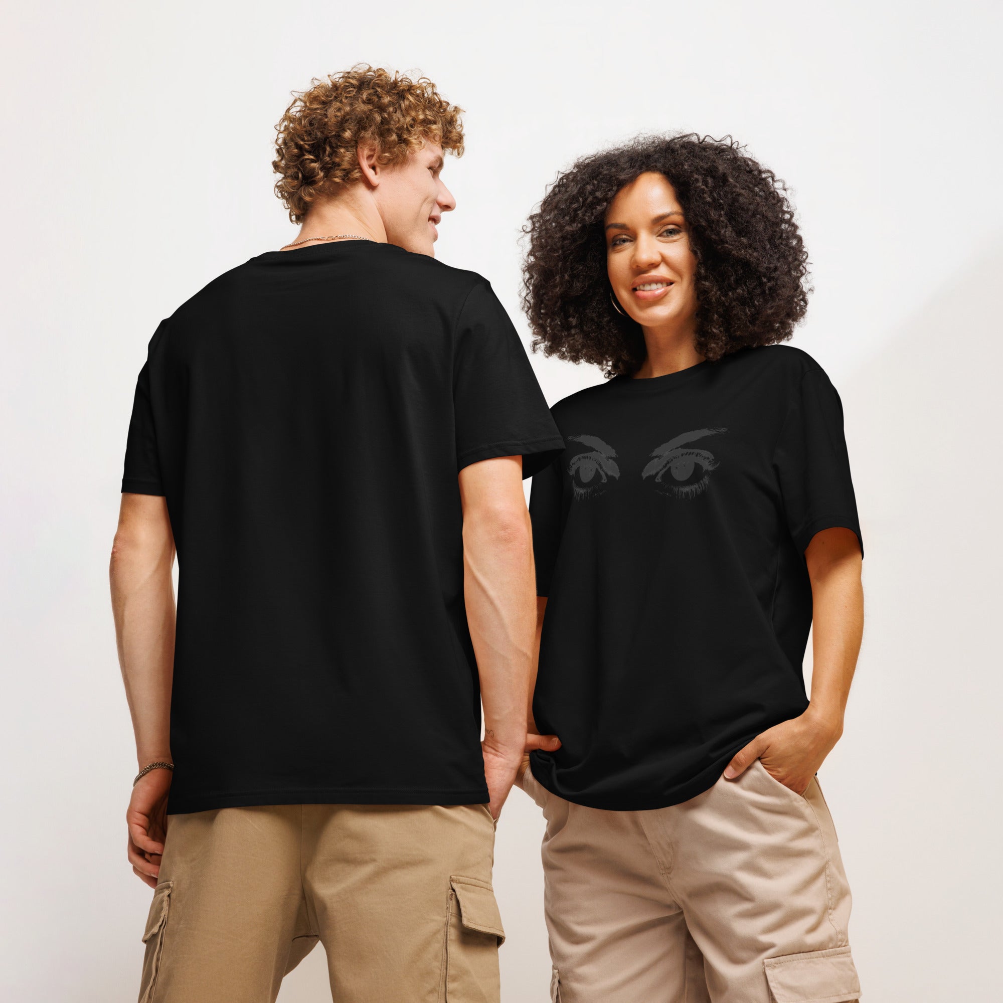 Two people wearing black graphic eyes t-shirts, standing side by side against a plain background